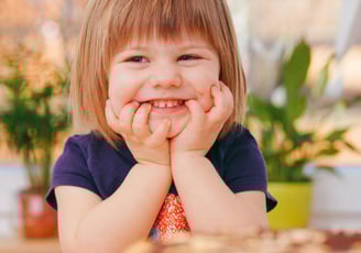 a little girl smiling at the table with a cake