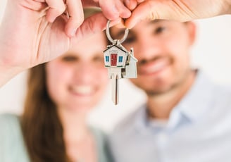 a man and woman holding keys to their house