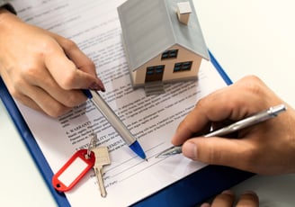a person holding a pen and writing on a clipboard