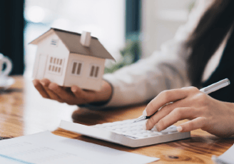 a woman is holding a house model and a pen