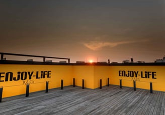 a sunset view of a city skyline with buildings and a sun setting