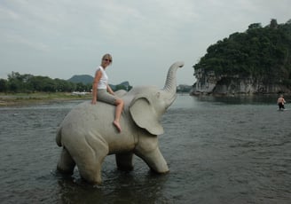 Tracey Billington on an elephant  by the river in Guilin, China