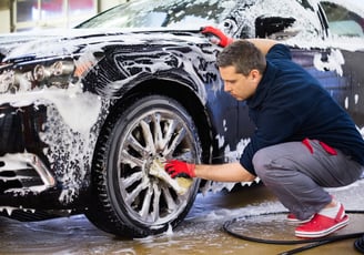 a man washing a car with foam foam