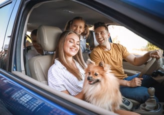 Família feliz com seu cachorro dentro carro com a janela aberta