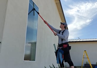 man washing tall exterior window pane