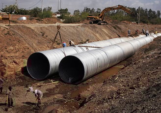 a group of people standing around a large pipe