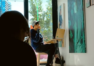 a man sitting on a chair in front of a painting
