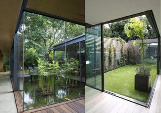 Patio interior con estructura acristalada y jardín integrado en arquitectura sostenible