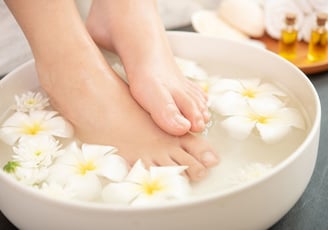 Voeten in een ontspannend voetenbad met bloemen en natuurlijke oliën.