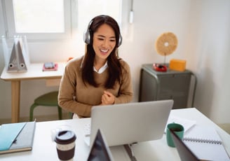 a woman with headphones at a laptop, engaged in an intensive language course with her tutor
