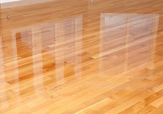 Newly finished hardwood floors shining under natural light, showcasing the rich texture & warm tones