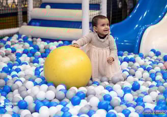 a baby girl in a ball pit with a ball in the middle of a ball