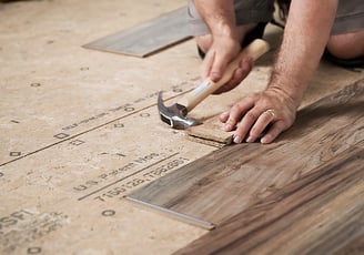 a man is using a hammer to install a laminate floor