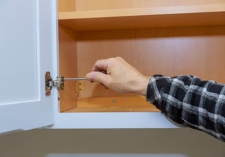 a person holding a screwdriver fixing a cabinet