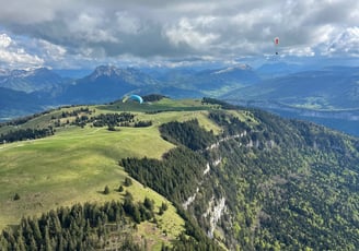 a person parasailing over a mountain range