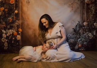 a woman in a white dress is holding a child for mother's day photos