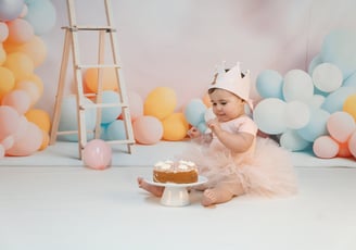 a baby girl in a pink tutu having her first birthday cake smash