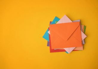 Stack of colorful envelopes on yellow background | Email marketing concept