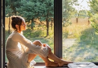 a woman sitting on a window sill meditating