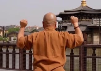 a man in a brown shirt and jeans standing on a bridge