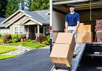 Man using a dolly to unload furniture and appliances from a box truck for delivery and assembly serv