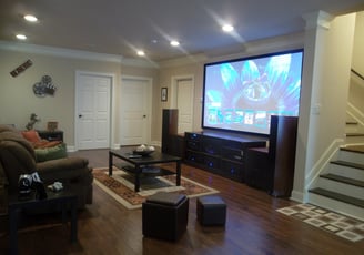 Large fixed frame projector screen mounted on a wall in a living room - home cinema room