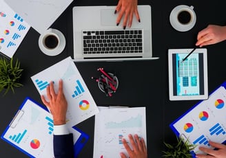 a group of people sitting around a table with printed charts