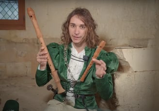 a man in a green jacket holding two wooden sticks