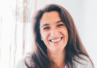 femme brune pull gris avec un grand sourir