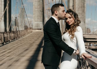 a bride and groom standing on a bridge