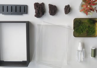 a terrarium kit with a frame rocks moss and plants.