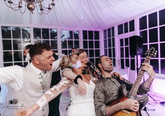 Bride and groom having fun with wedding singer musicians and band