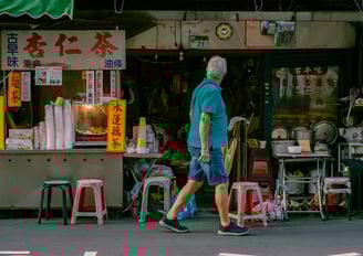 a man walking down the street in front of a Taiwanese street food vendor