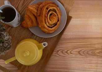 Plateau de table en bois naturel avec bord live edge, vu de près. Seul un plateau de déjeuner est posé dessus, occupant presq