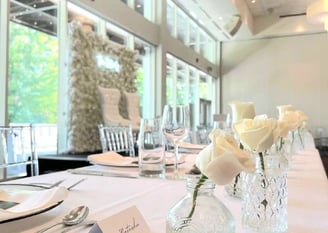 White rose flower wall with matching white roses in vases with tableware