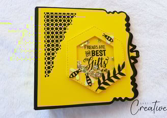Yellow handmade photo album with a hexagonal window featuring bees and sequins. Text reads, "Friends