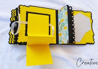 Handmade photo album with scalloped edges features bright yellow, black, and floral patterns. A whit
