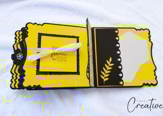 Handmade album with decorative yellow and black pages. The left page has a ribbon and text; the righ