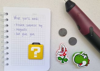 A notepad with a list of DIY materials, including a Kinder Surprise toy, magnets, and a hot glue gun