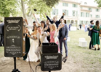 Newlyweds and guests laughing in front of wedding photo booth — South of France photographer cost