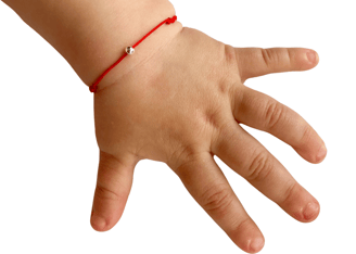 a child's hand holding a bracelet with a red string bracelet