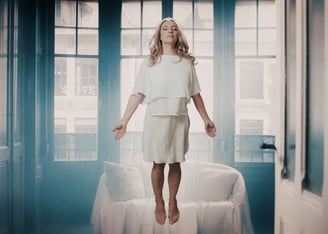 a woman in a white dress floating in front of a window