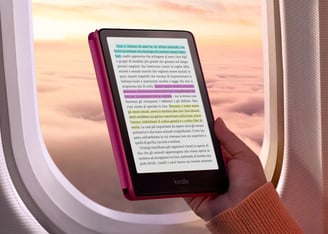 Persona leyendo un Kindle dentro de un avión al atardecer, destacando la portabilidad y comodidad de