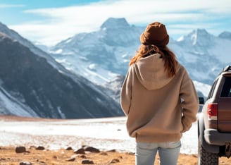 Traveler woman next to her car observing the snowy mountains.