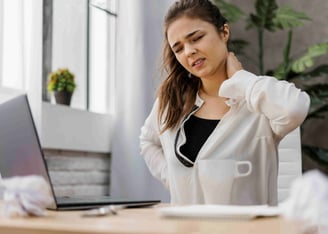 Woman having a neckache while working at home.