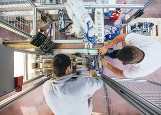 two men working on a robotic machine that is being worked on and upgraded