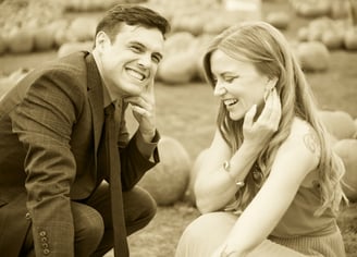 a man and woman in a field of pumpkins smiling in sepia style