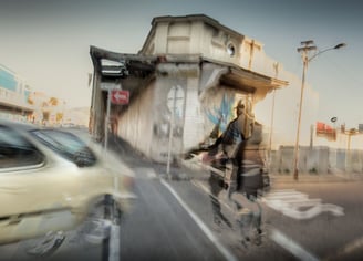 Energetic abstract photo of a cyclist, car, and street corner in Salt River, Cape Town, blending urban textures and movement.