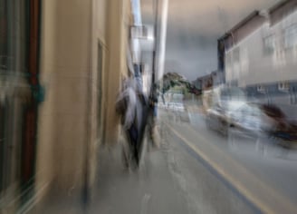 Abstract Cape Town street photograph showing a layered impression of a woman in a headscarf walking past cars and buildings