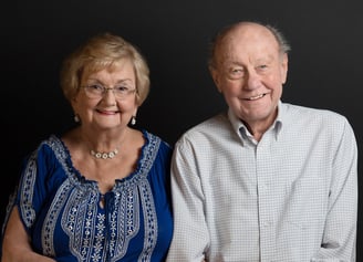 a man and woman sitting next to each other smiling holding hands